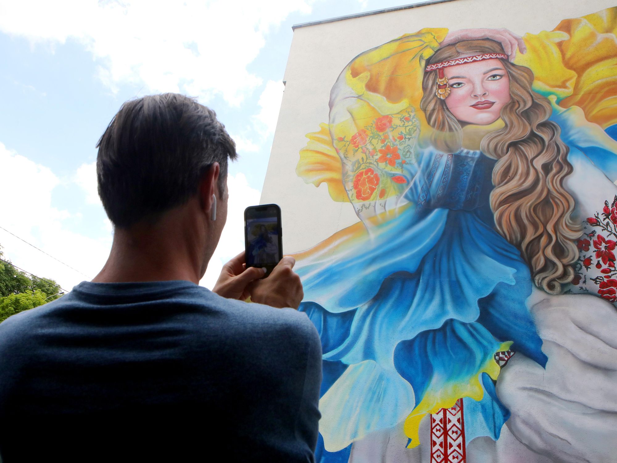 A man takes a photo of a mural in support of Ukraine
