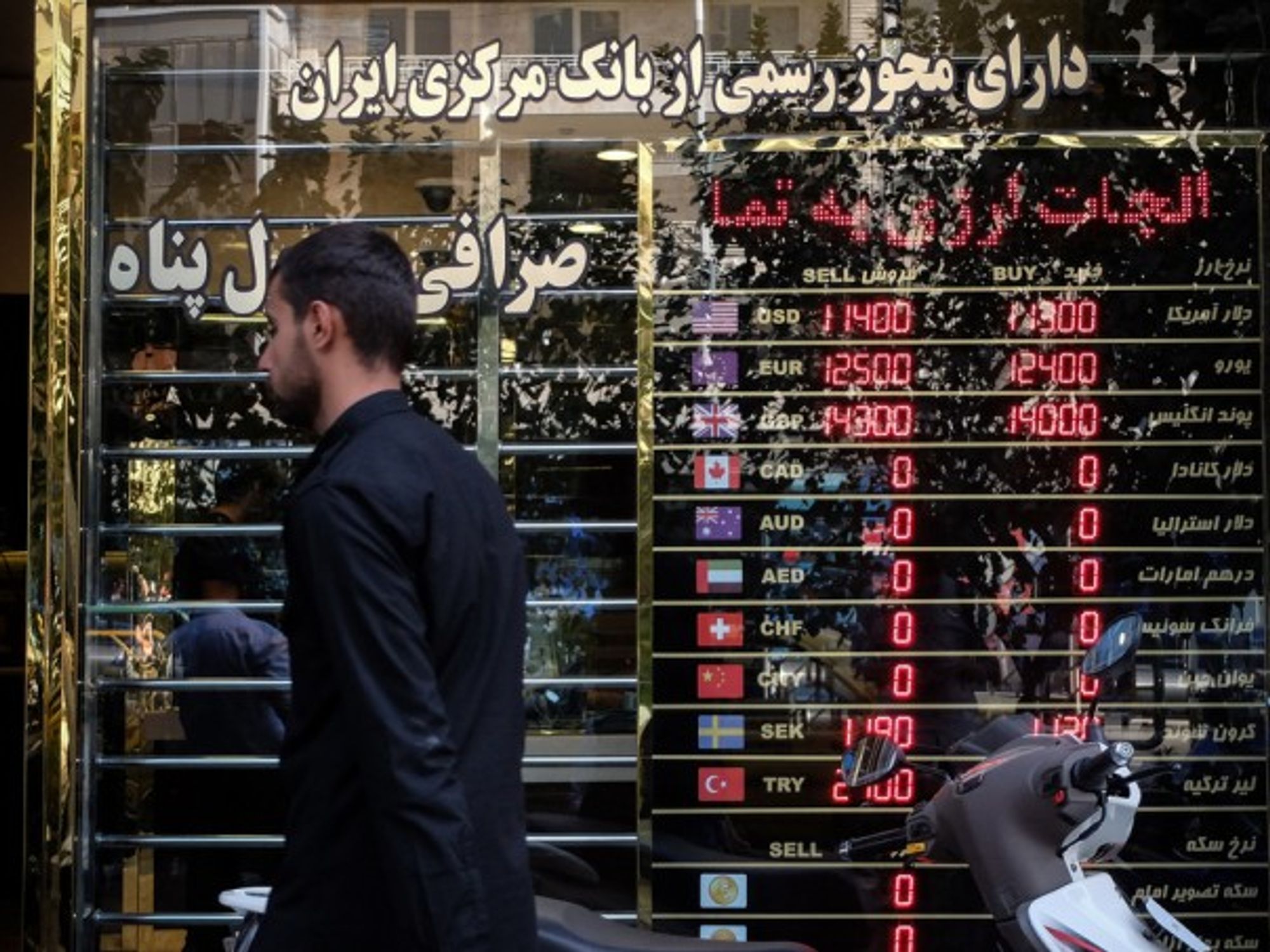 A man walking past a currency exchange shop in Tehran