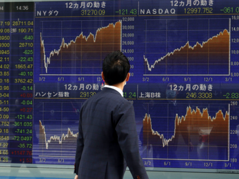 A man walking past a Nikkei stock index in Tokyo, Japan.