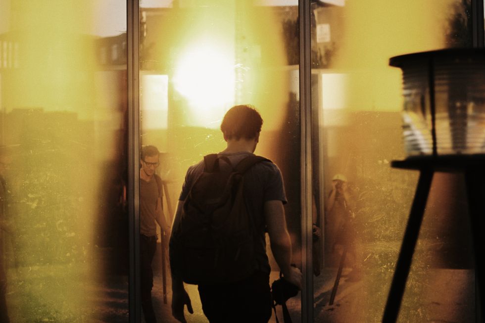 A man walking with his backpack on passing other people.