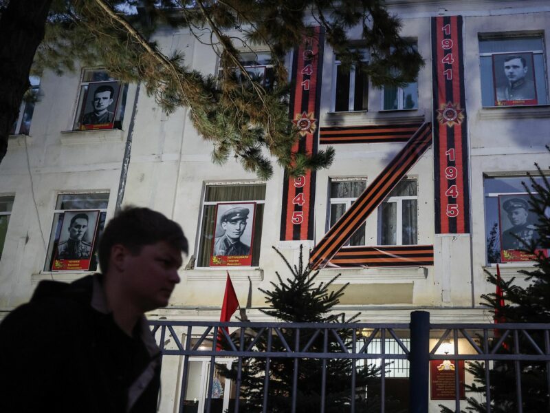 A man walks past a building marked with the Russian Army Z.