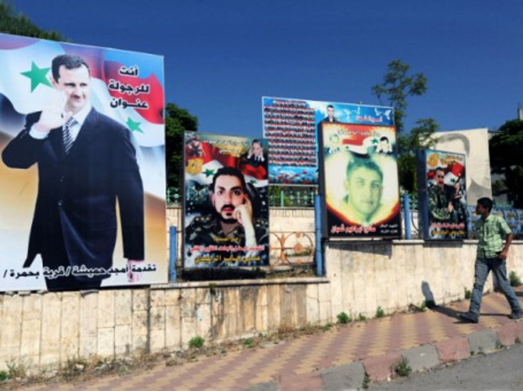 A man walks past a poster of Syrian President Bashar al-Assad in Latakia