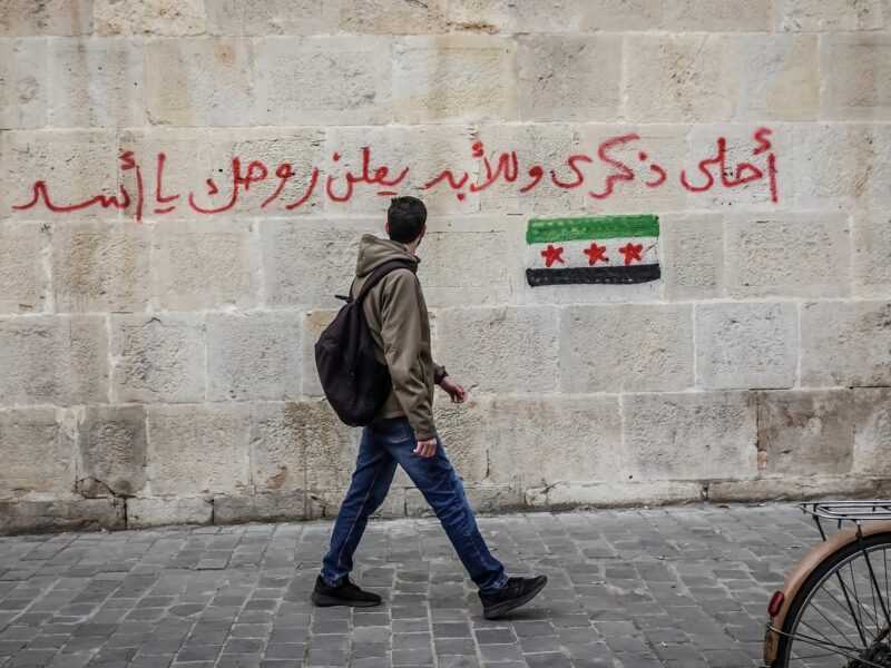 A man walks past graffiti that states ''Best souvenir forever: f*#k you Assad," Damascus, Syria, Dec. 11, 2024.