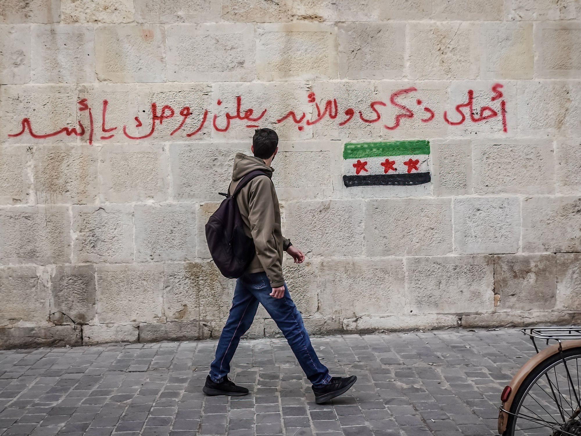 A man walks past graffiti that states ''Best souvenir forever: f*#k you Assad," Damascus, Syria, Dec. 11, 2024.