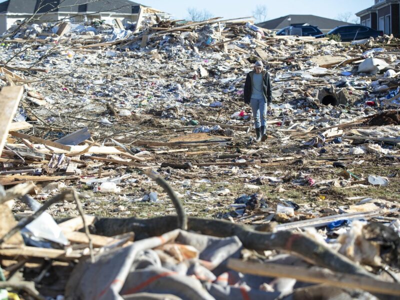 A man walks through the wrecked remains of houses in a neighborhood off Russellville Road after a tornado swept through Friday night