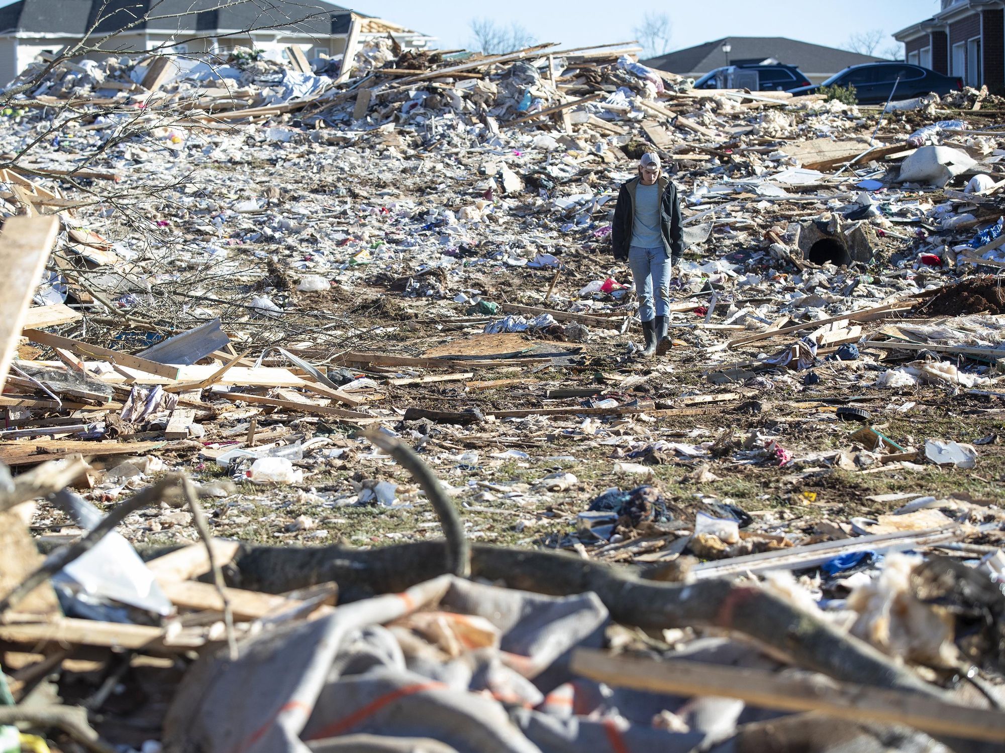 A man walks through the wrecked remains of houses in a neighborhood off Russellville Road after a tornado swept through Friday night