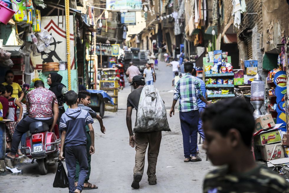 A man walks while carrying a suck of rubbish on the street of Mokattam in Cairo.​