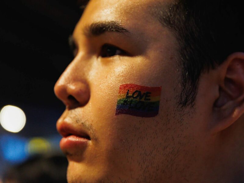 A man with a rainbow flag on his cheek at the Bangkok Pride Parade in Thailand