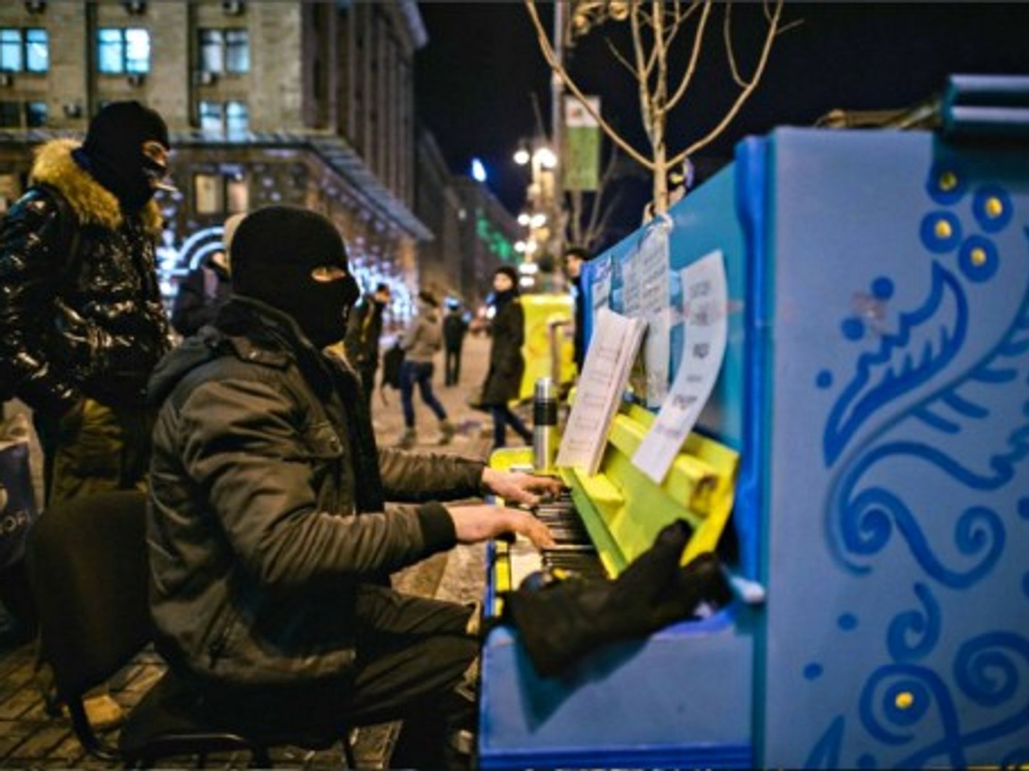 A masked protester plays the piano in front of Kiev's occupied City Hall