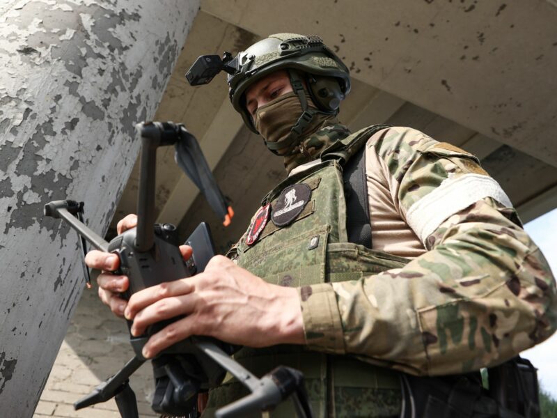 A masked Russian unmanned aerial vehicle (UAV) unit serviceman holds a copter