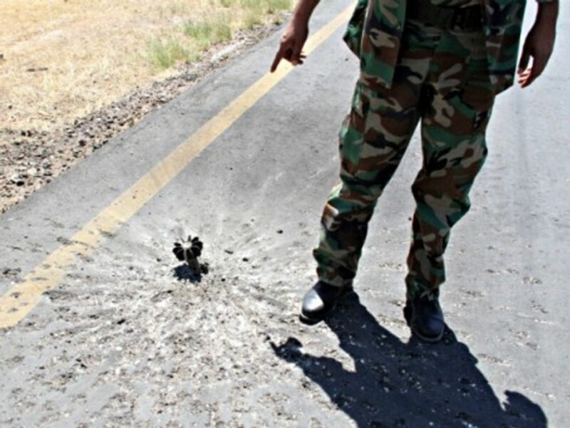 A militia soldier points out a shell stuck on the tarmac of Tripoli's International Airport, in Libya, on July 16.