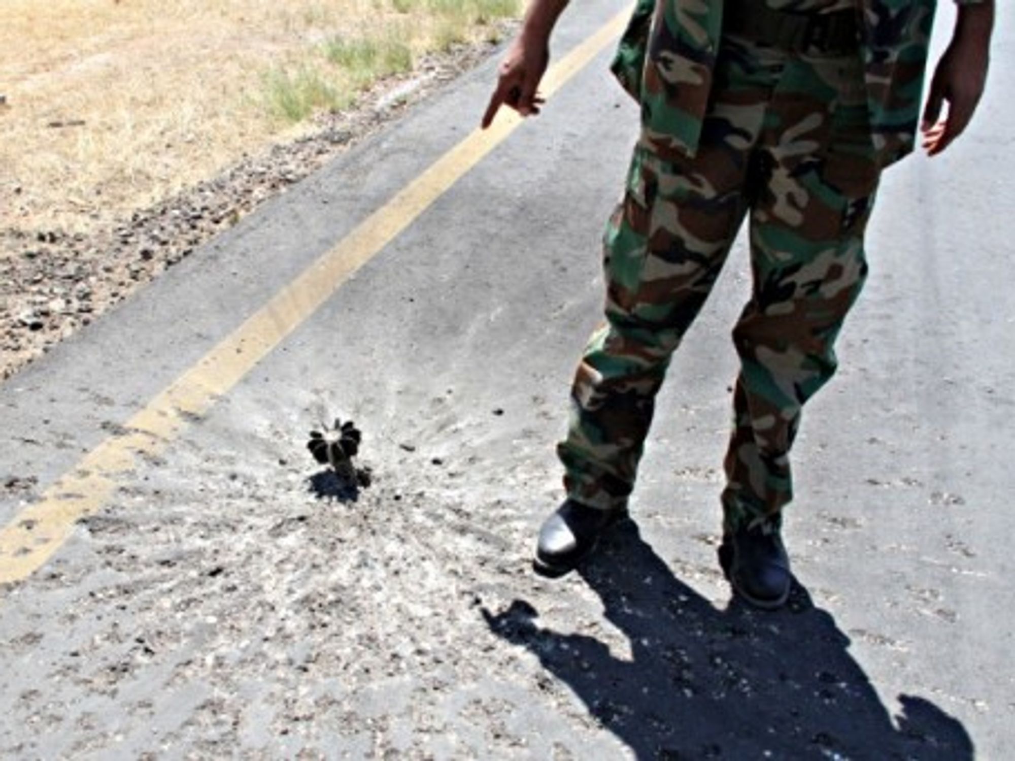 A militia soldier points out a shell stuck on the tarmac of Tripoli's International Airport, in Libya, on July 16.