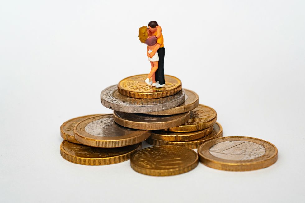 A miniature of a couple kissing on a mountain of coins