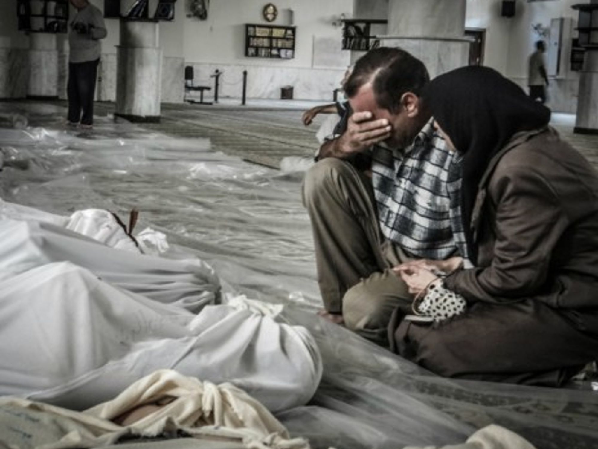 A mother and father weep over the body of their child, killed in a suspected chemical weapons attack on Damascus