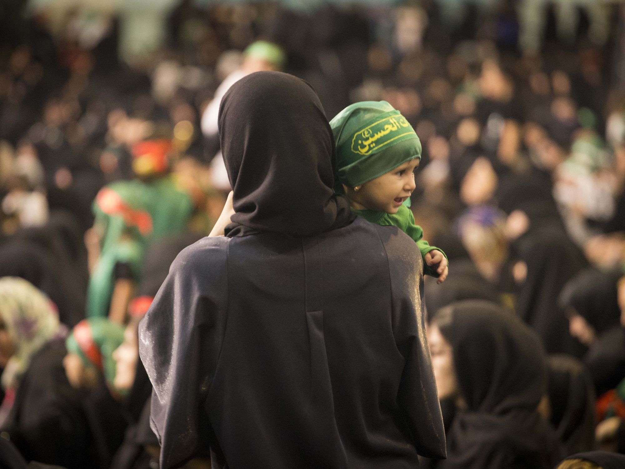 A mother in black with her back turned holding a baby