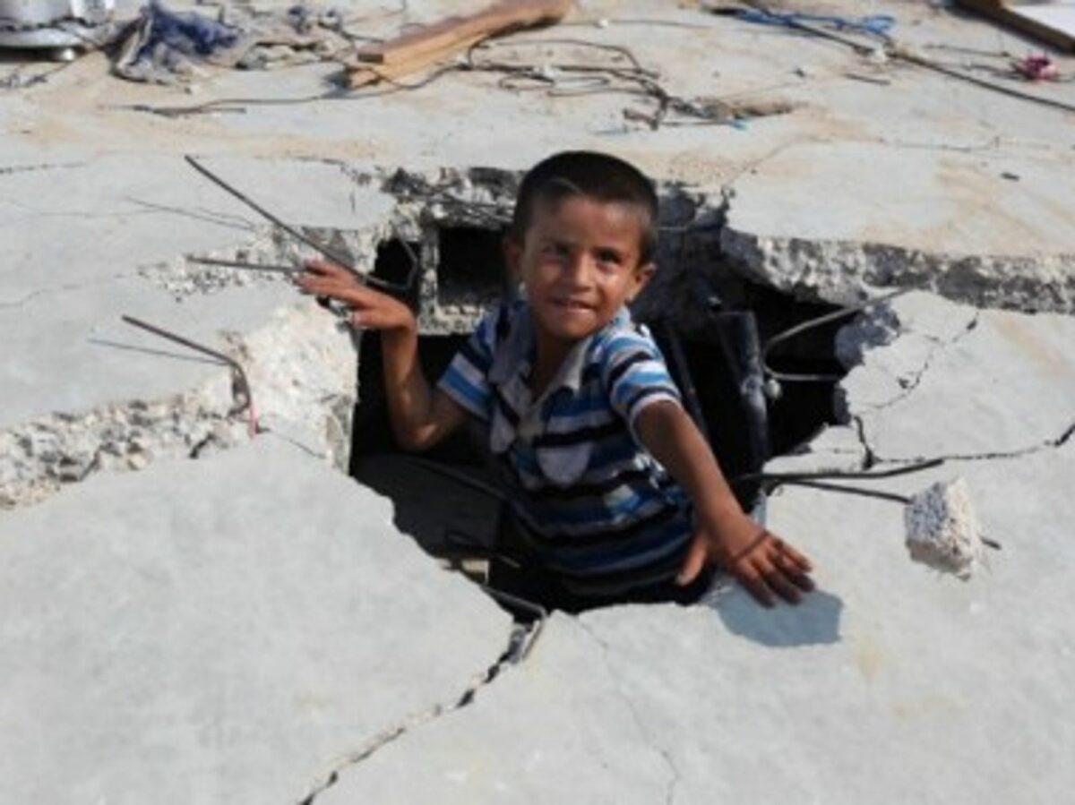 A Palestinian boy plays amid the rubble of his destroyed family home.