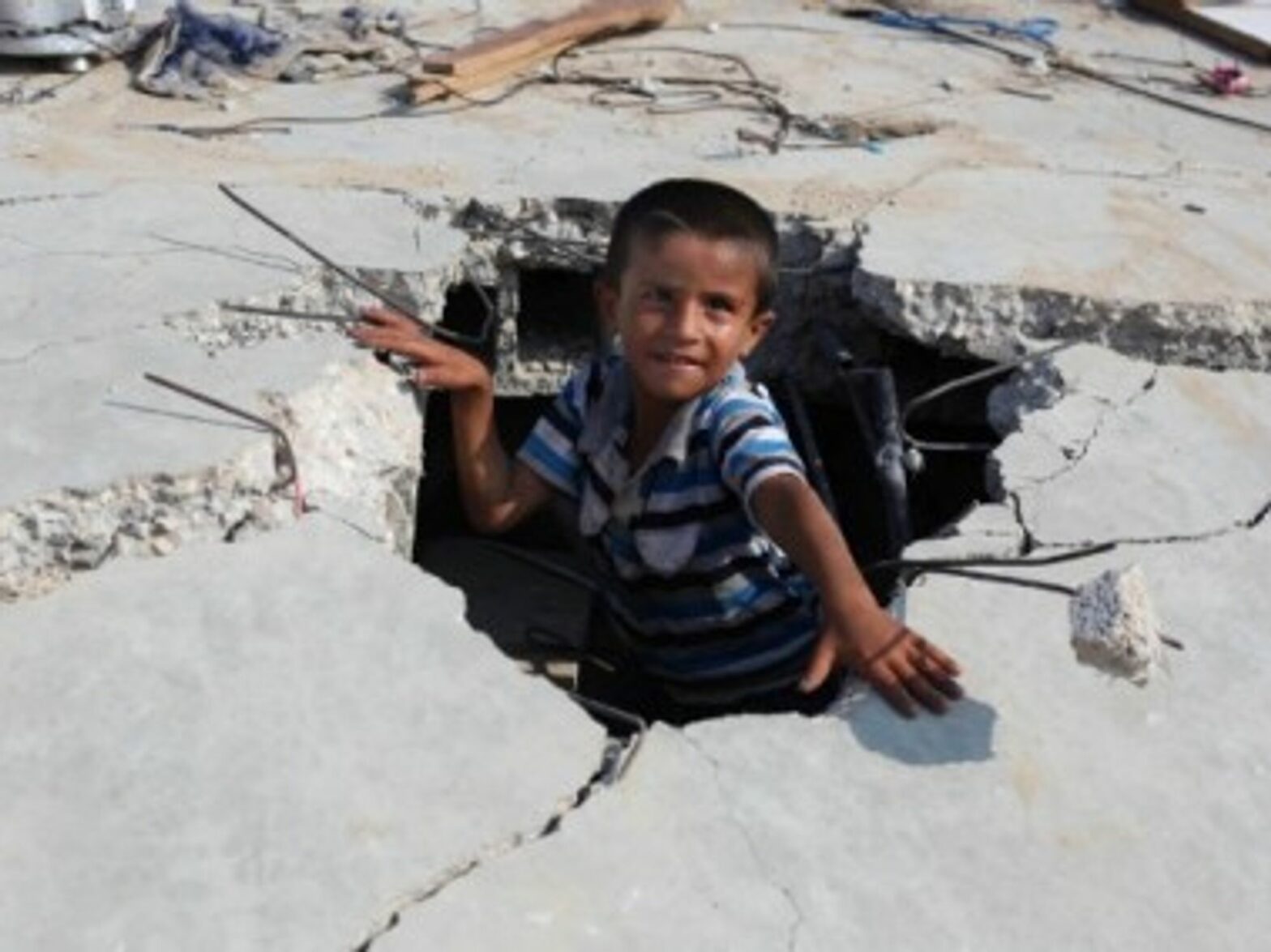 A Palestinian boy plays amid the rubble of his destroyed family home.