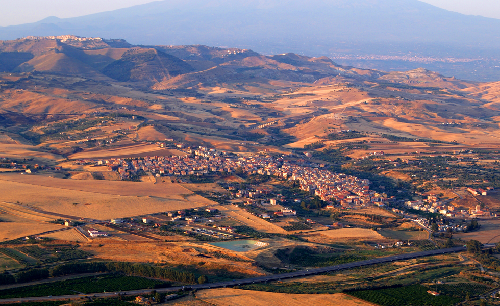 A panoramic photo of the town of Catenanuova under golden light.