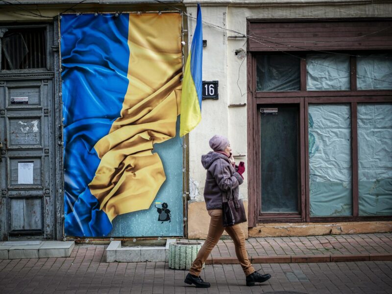 A passer-by walks past a house with the flag of Ukraine in the old town.