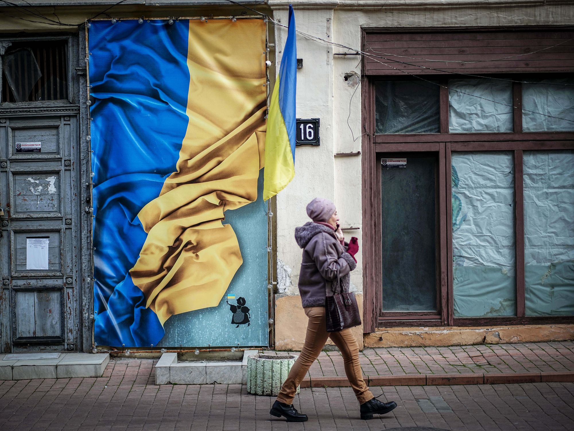 A passer-by walks past a house with the flag of Ukraine in the old town.