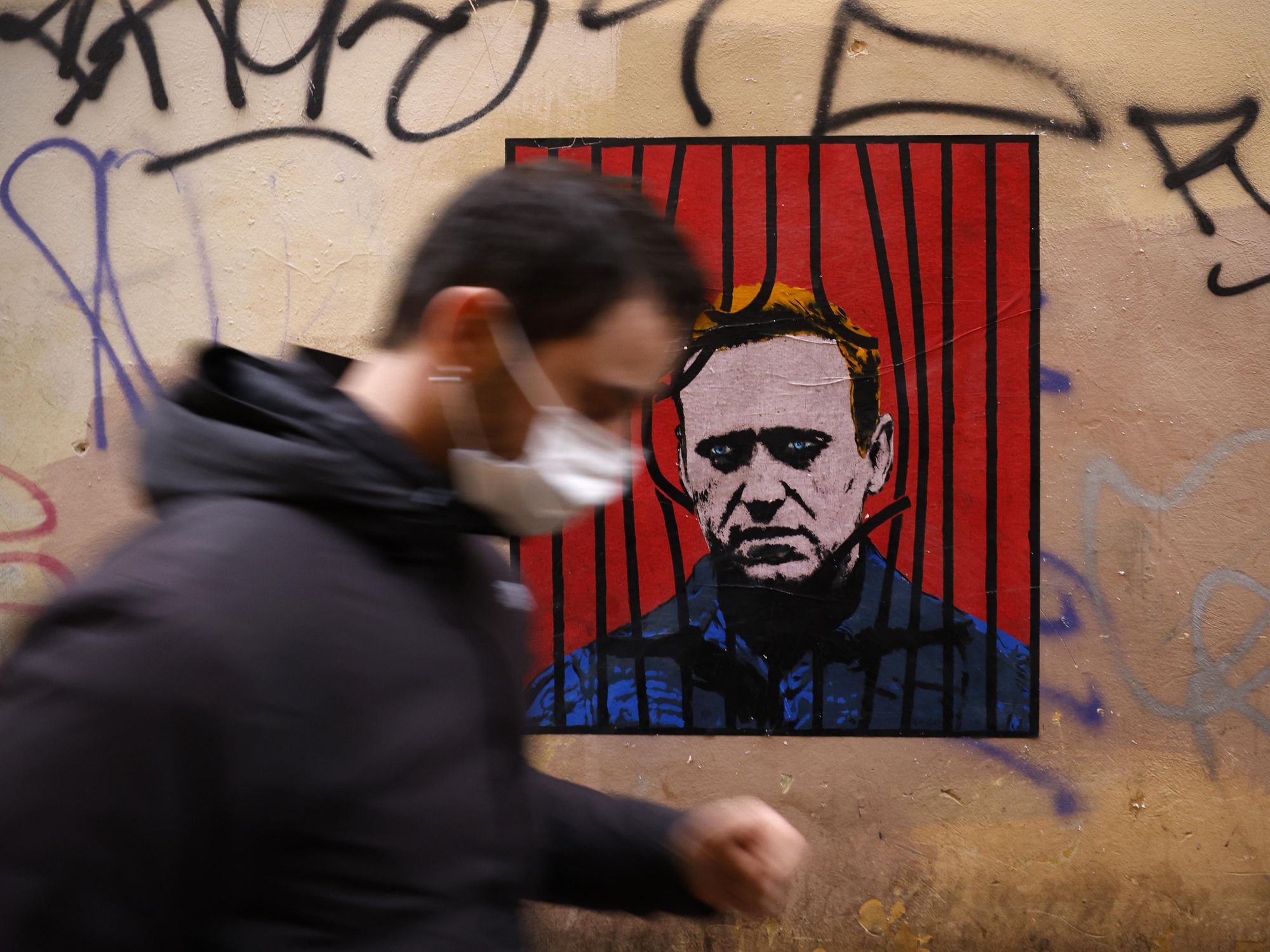 A passerby passing in front of a street art of Russian opposition leader Alexei Navalny in Rome, Italy