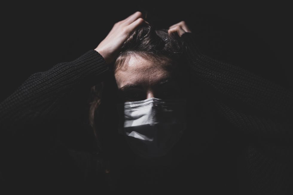 A person covers her face with a face mask.