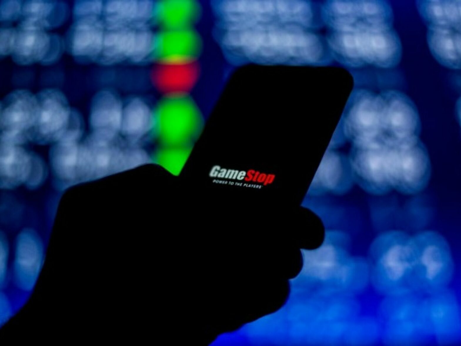 A person looks at the screen on their mobile phone, which shows the 'Gamestop' logo