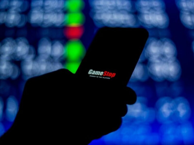 A person looks at the screen on their mobile phone, which shows the 'Gamestop' logo