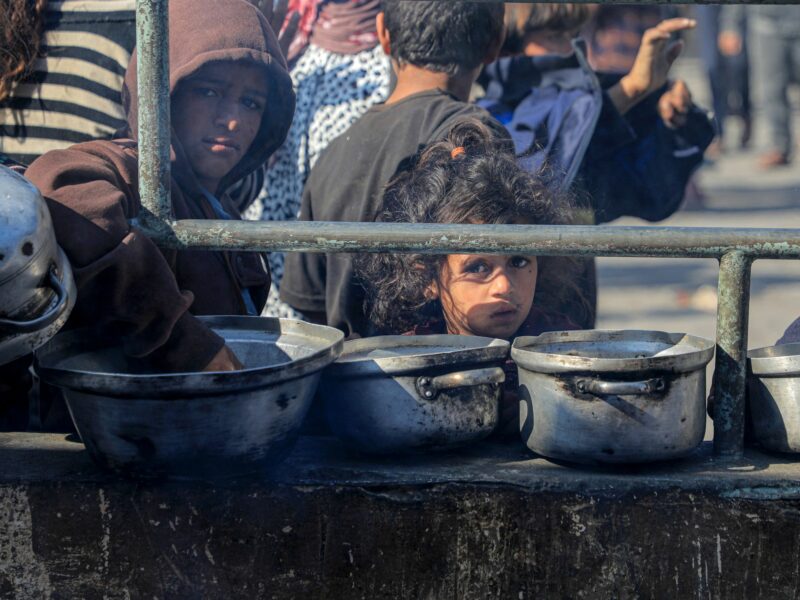 A photo of a displaced child in Gaza can be seen waiting for food
