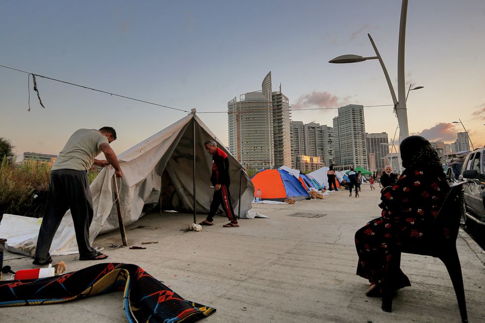 A photo of a Lebanese family that fled Beirut southern suburb, a stronghold of pro-Iranian Hezbollah erects a makeshift tent opposite luxurious buildings.
