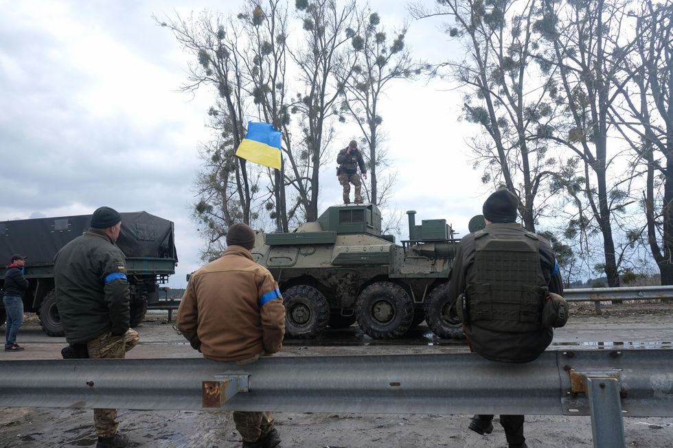 A photo of a Ukrainian soldier standing on a Russian tank