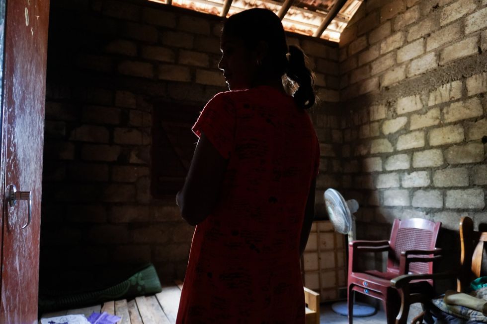 A photo of a woman in a small room with her back turned to the camera