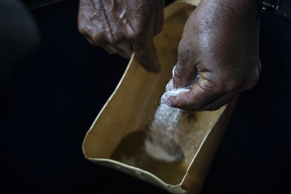A photo of a worker sprinkling Caucasian soda over water with coca alkaloid in a ''laboratory'' where coca leaves are processed into coca paste.