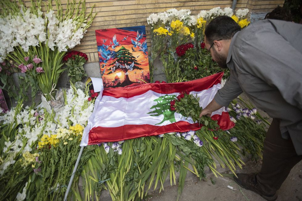 A photo of man places flowers at the site of a memorial set up outside Lebanon's embassy in Tehran, on September 18, 2024.