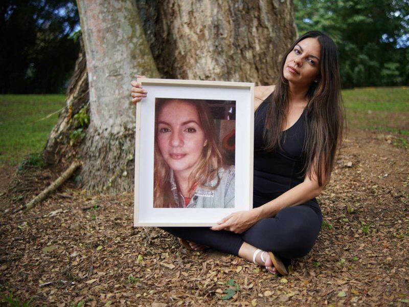 A photo of Paola Correa posing with a portrait of her sister