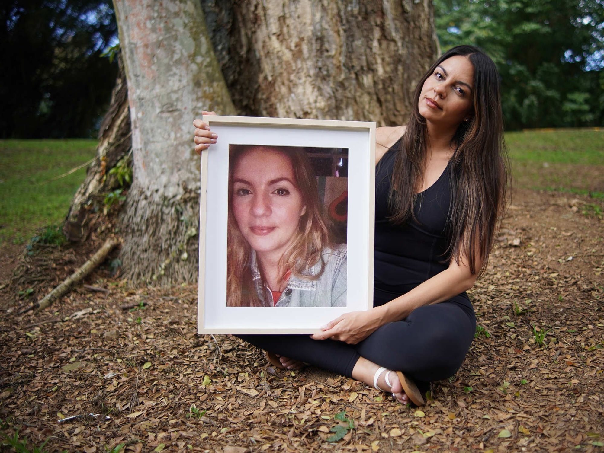A photo of Paola Correa posing with a portrait of her sister