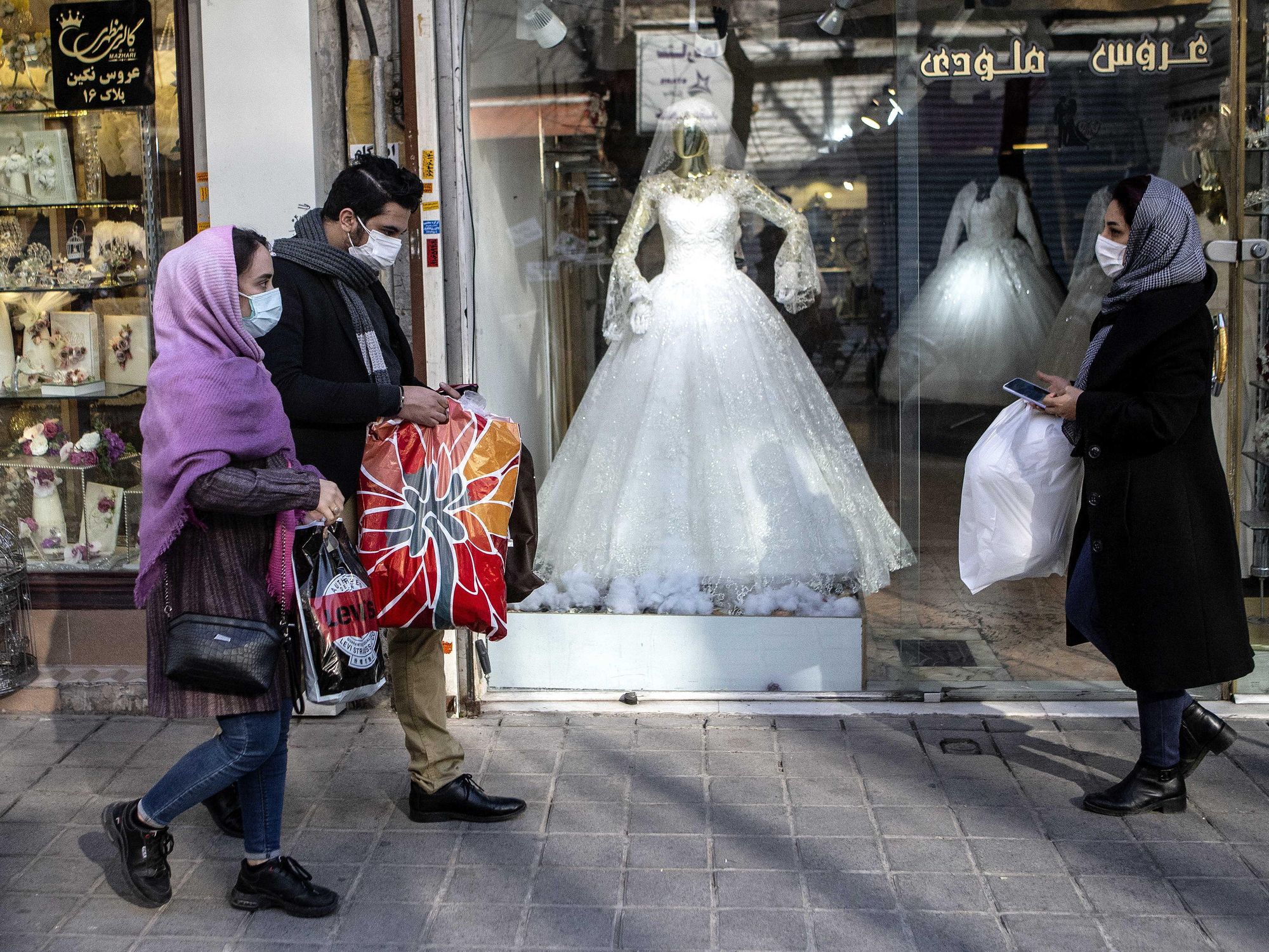 A photo of people walking past a bridal shop