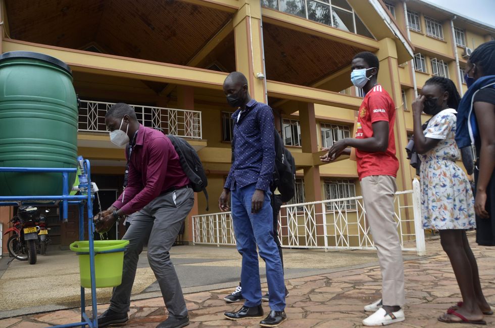 A photo of students lining up to wash their hands from a green water tank