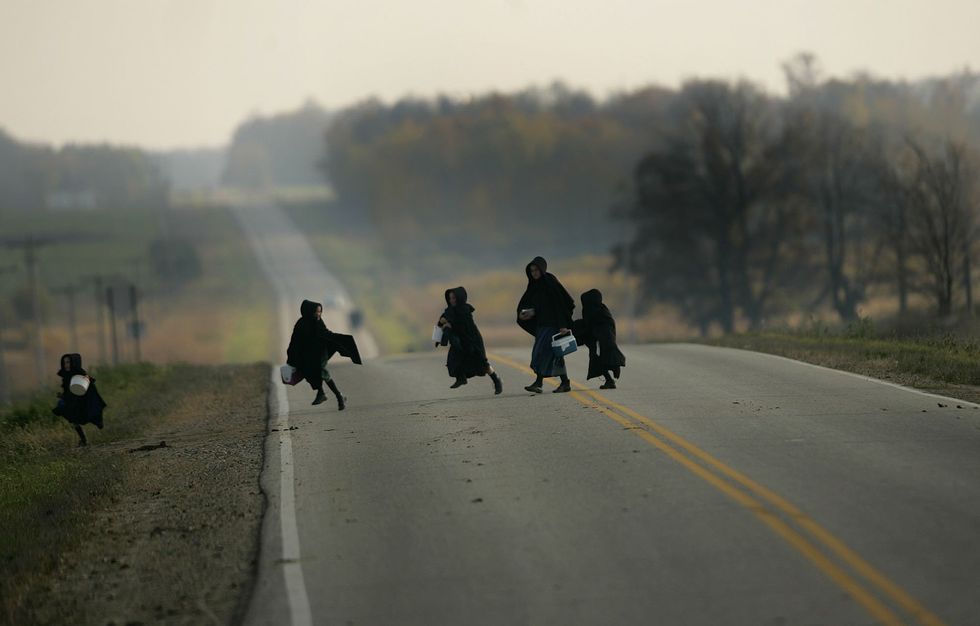 A photo of young Amish girls cross a county highway on their way home from school Thursday, Oct. 13, 2005, in Todd County in central Minnesota.