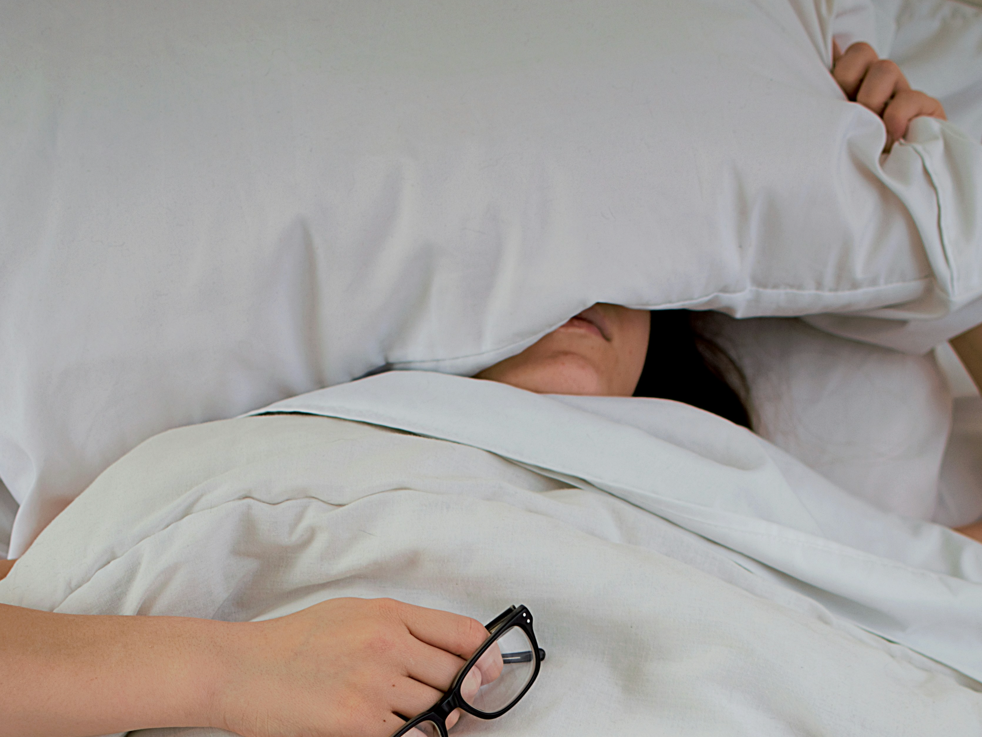 A photograph of a woman trying to sleep in a bed.