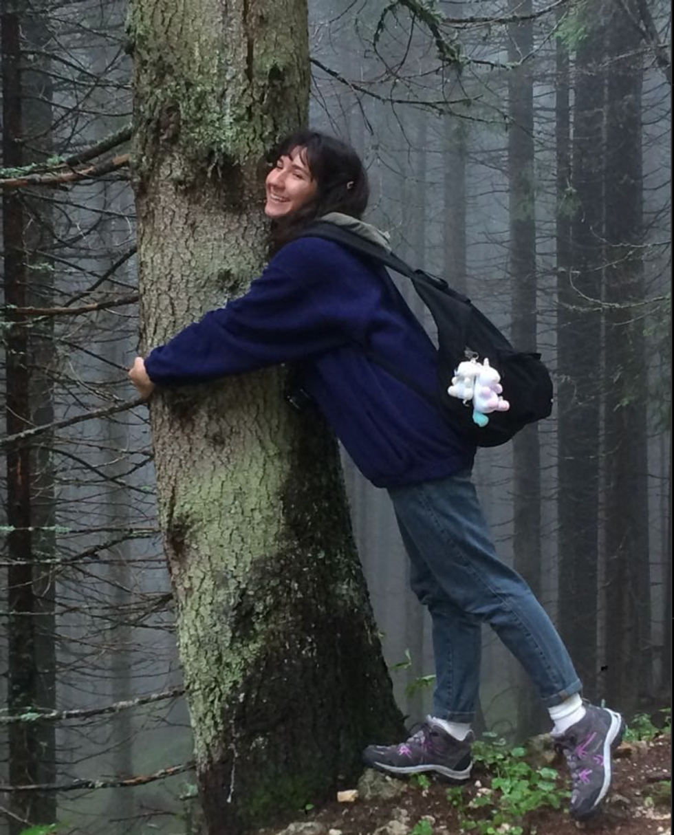 A photograph of Giulia Cecchettin hugging a tree in a forest.