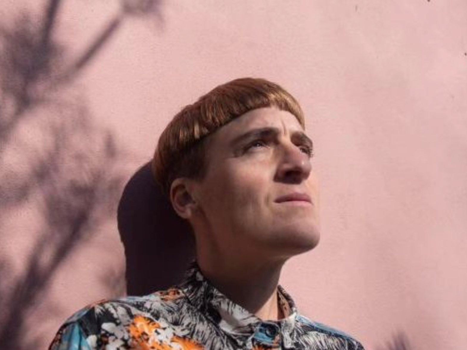 A photograph of writer ​María Candelaria Schamun, standing in front of a light pink wall.