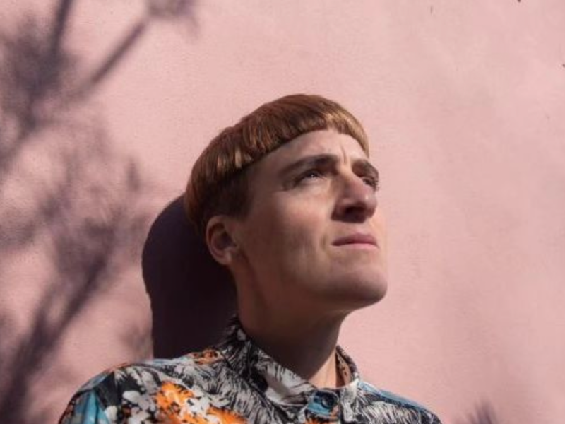 A photograph of writer ​María Candelaria Schamun, standing in front of a light pink wall.