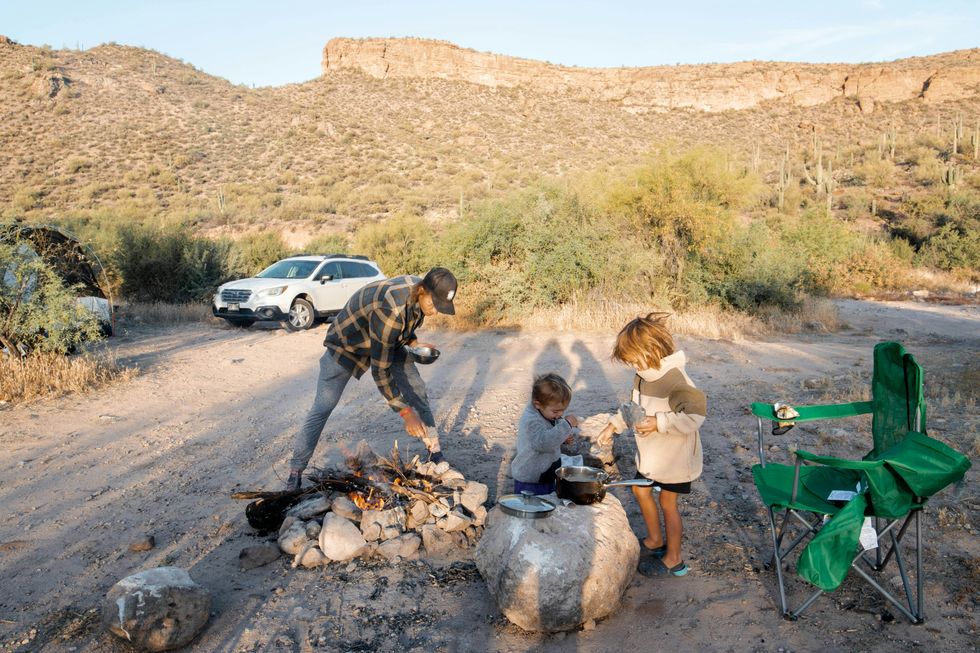 A picture of a father and his two children camping in nature in the U.S.