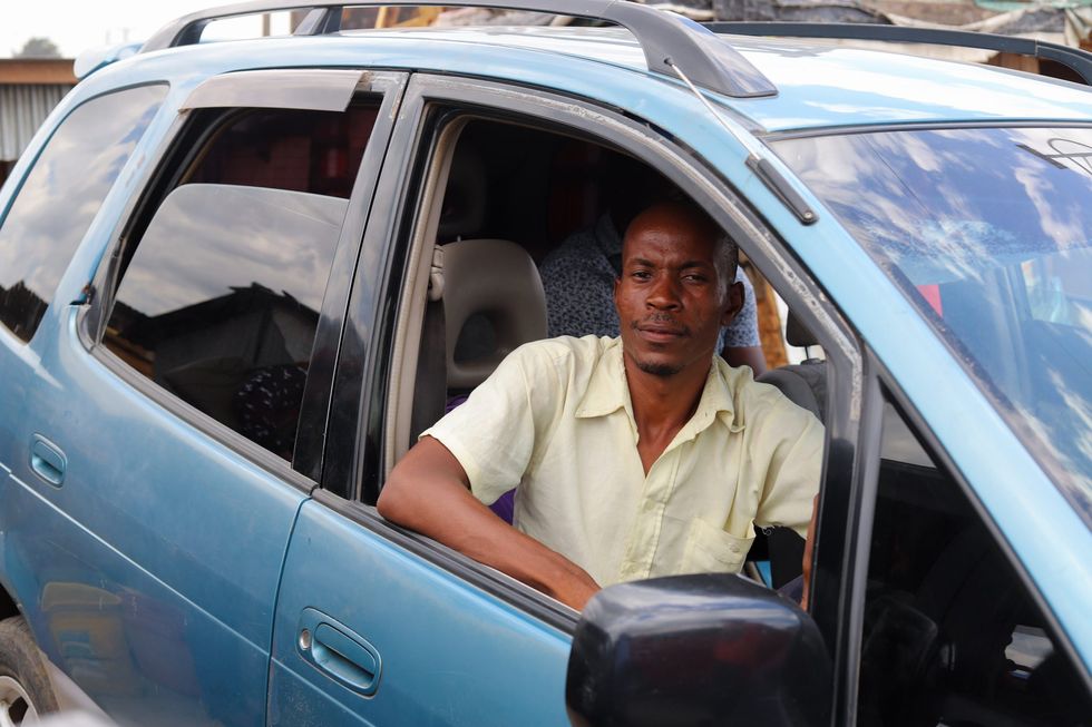 A portrait of Kennedy Kalumbu sitting in his taxi in Lusaka.