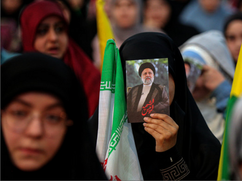 A pro-Iranian Hezbollah supporter displays a picture of late Iranian President Ebrahim Raisi as she attends a mass rally in Beirut southern suburb to mark his death earlier this week.