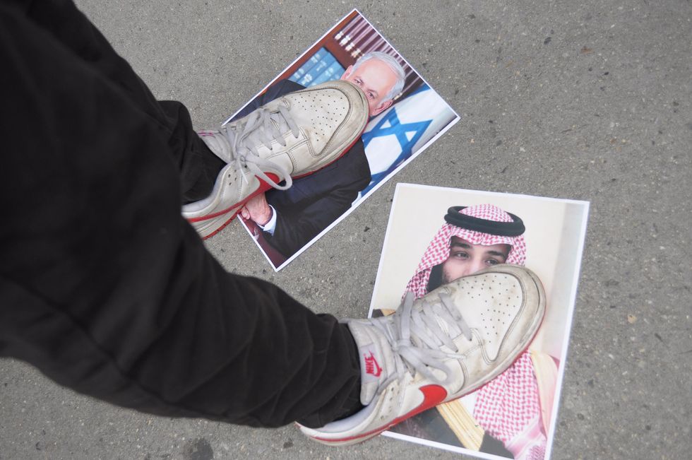A pro-Palestine protester steps photos of Israeli Prime Minister, Benjamin Netanyahu and Mohammed bin Salman, right at a rally in Manhattan.