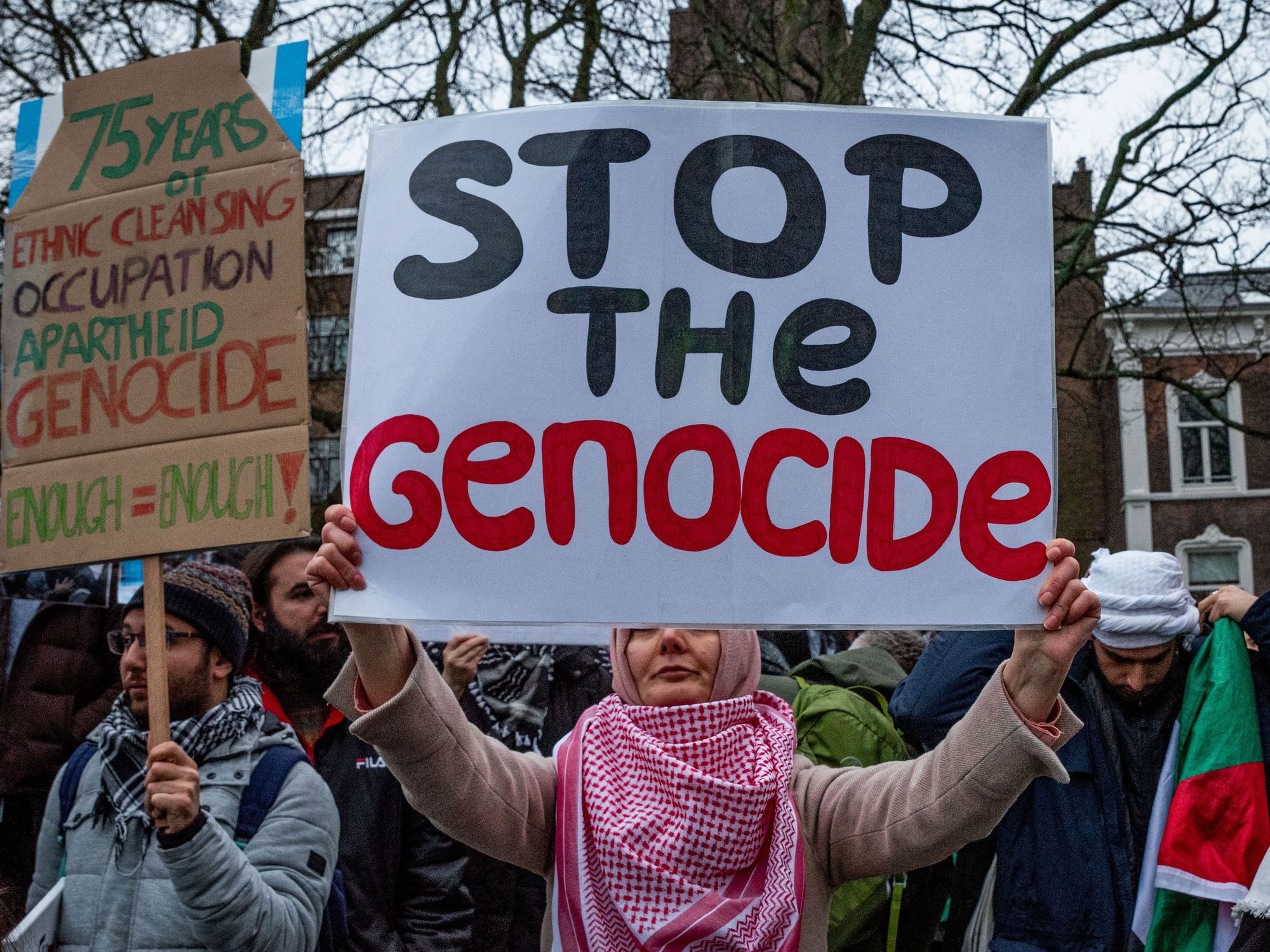 A pro-Palestinian demonstrator carries a protest sign reading ''Stop the Genocide.'' On January 12, 2024, pro-Israel and pro-Palestine activists demonstrated at the International Court of Justice in The Hague.