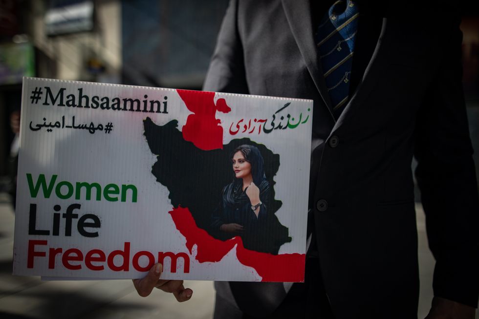 A protester carries a sign with an image of Mahsa Amini, a young woman murdered for not wearing the Islamic veil properly in 2022.