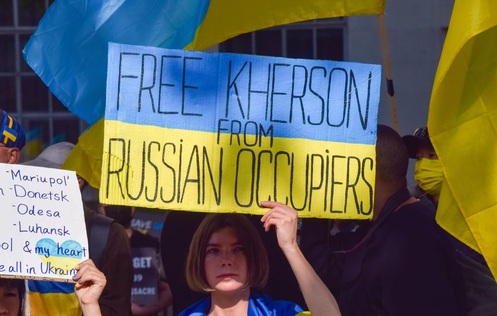 A protester holds a placard which reads 'Free Kherson from Russian occupiers'.